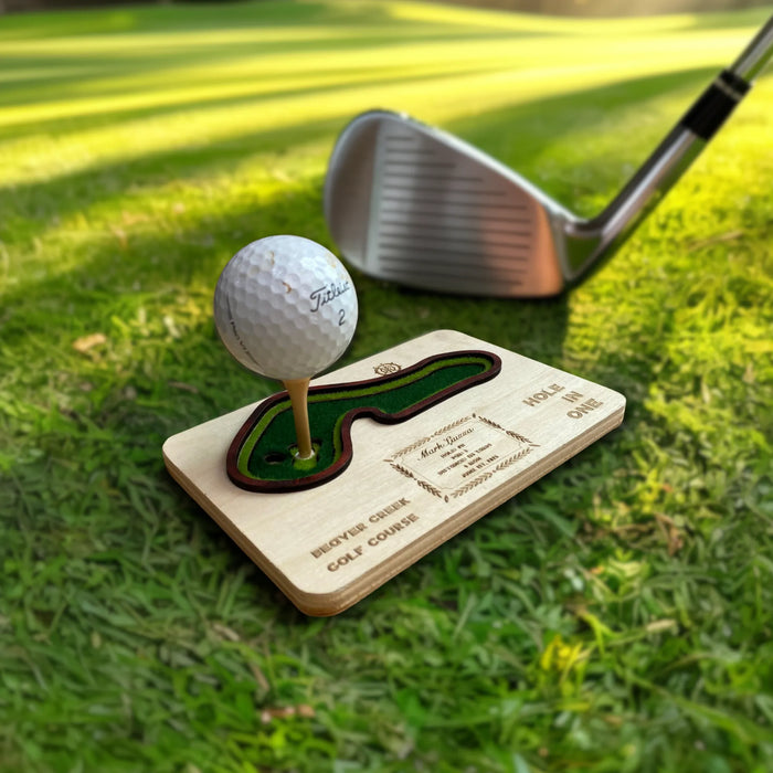 Hole in one display with Golf ball on a wooden tee with a golf club in the background on grass
