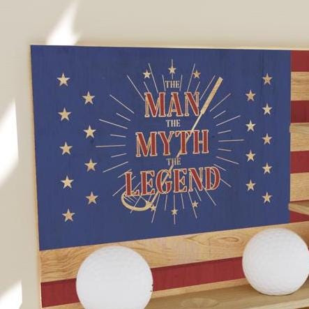 Decorative sign with 'The Man, The Myth, The Legend' text on a blue background with stars, placed against an American flag.