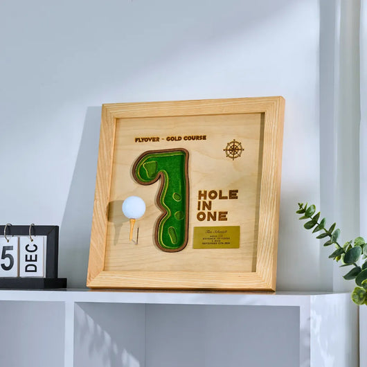Wooden plaque with golf design and 'Hole in One' text on a shelf.