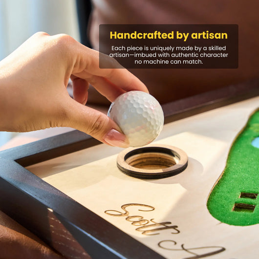 Hand holding a golf ball over a wooden golf ball holder with text about artisan craftsmanship.