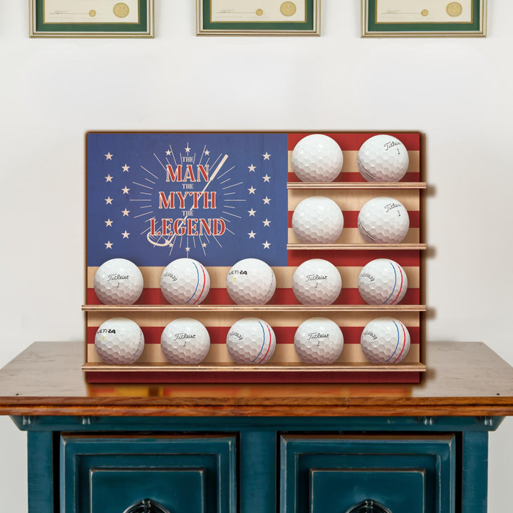 Golf ball display with 'The Man Myth Legend' design on a flag background.