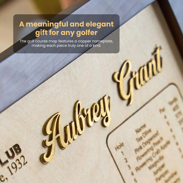 Golf course map with a copper nameplate featuring 'Aubrey Grant' on a wooden surface.