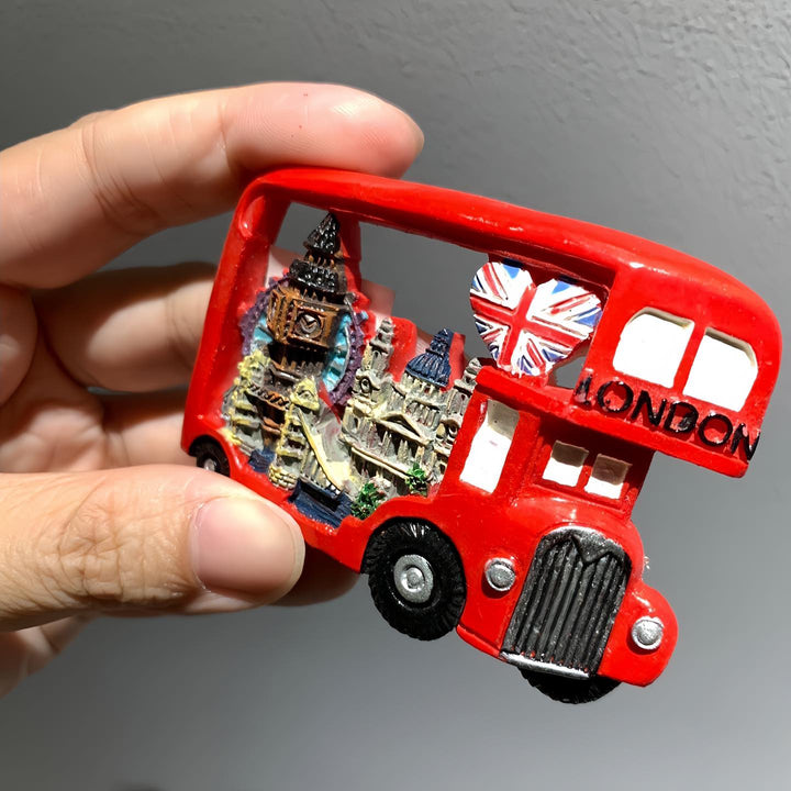Red London bus-shaped magnet with Big Ben and British flag design held by a hand against a gray background