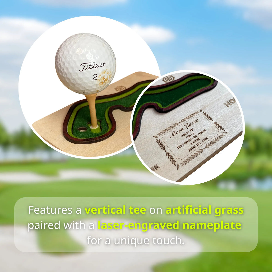 Golf ball on a vertical tee with artificial grass and laser-engraved nameplate, set against a golf course background.