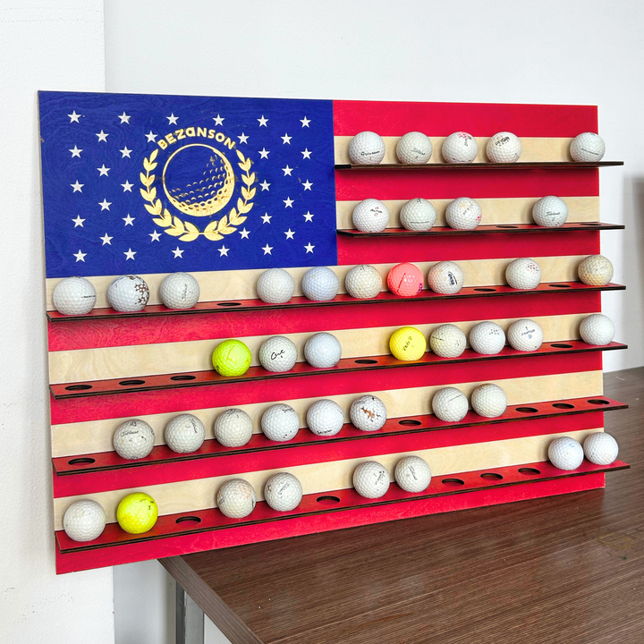 Golf ball display rack shaped like an American flag with golf balls on a wooden floor.
