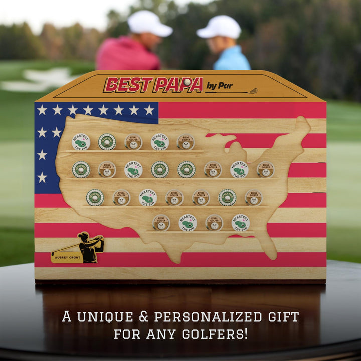 Wooden gift box shaped like the United States with golf-themed items on a blurred golf course background.