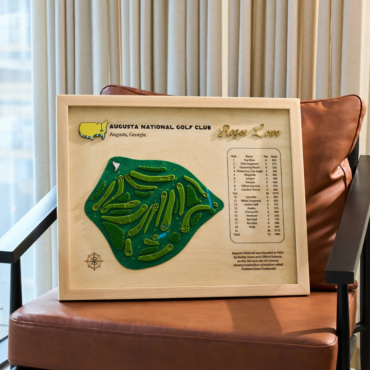 Framed map of Augusta National Golf Club on a brown chair with curtains in the background