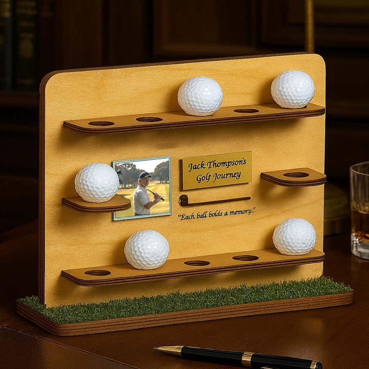 Wooden golf ball display with four golf balls and a photo frame on a grassy base.