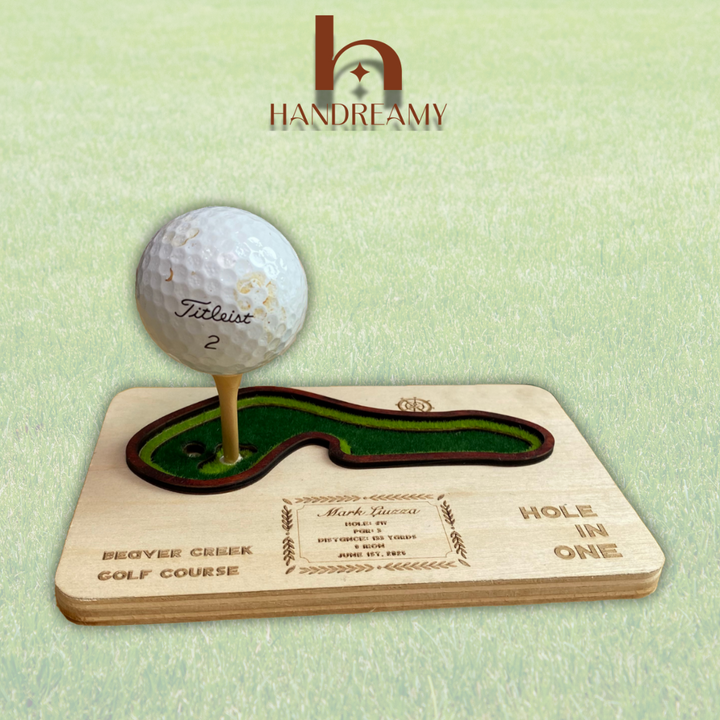 Golf ball on a wooden plaque with golf course design, featuring the Handreamy brand.