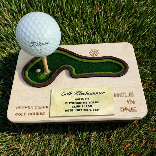Golf ball on a wooden tee with a miniature golf course design, placed on grass.